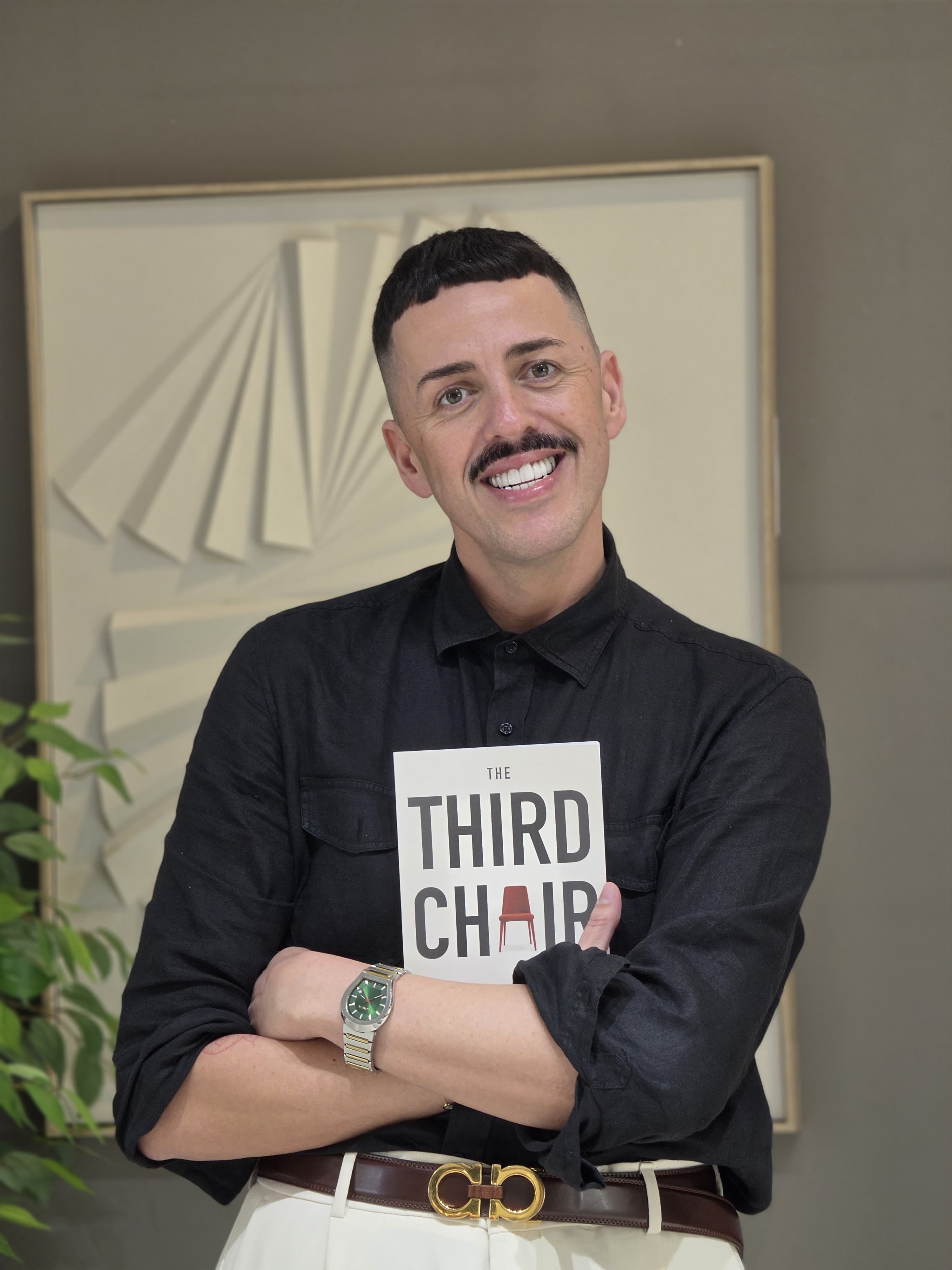 Dragan Andric smiling and holding a physical copy of The Third Chair.